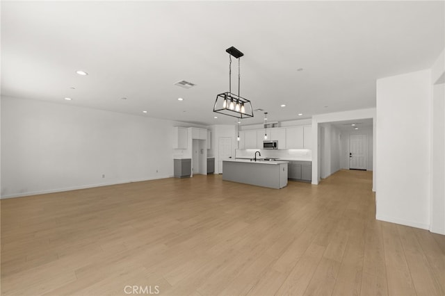 unfurnished living room with recessed lighting, visible vents, light wood-style flooring, and baseboards