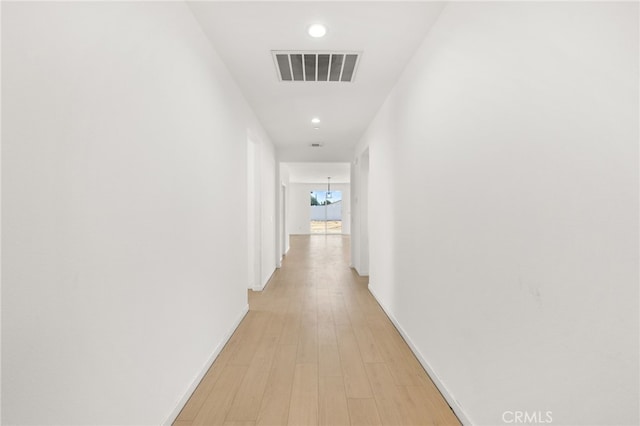 corridor featuring visible vents, baseboards, light wood-type flooring, recessed lighting, and an inviting chandelier