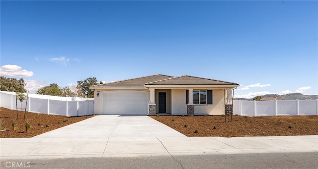 view of front of property featuring stucco siding, concrete driveway, an attached garage, and fence