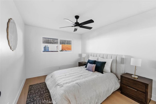 bedroom with a ceiling fan, light wood-style flooring, and baseboards