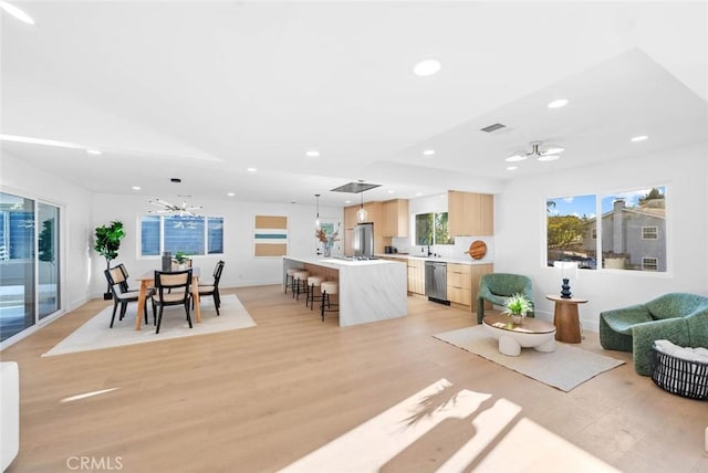 living area featuring recessed lighting, baseboards, visible vents, light wood-type flooring, and ceiling fan with notable chandelier