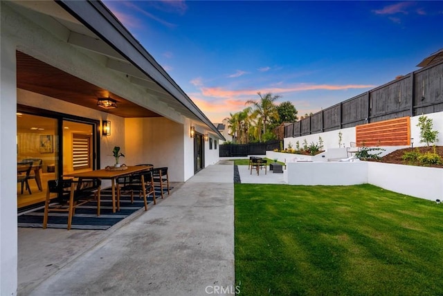 yard at dusk featuring a patio area and fence