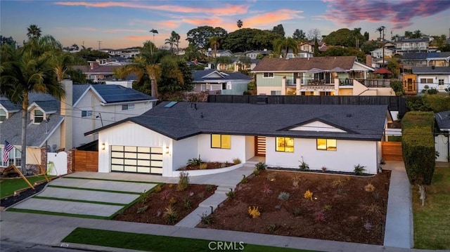 view of front of house featuring a garage, a residential view, driveway, and fence