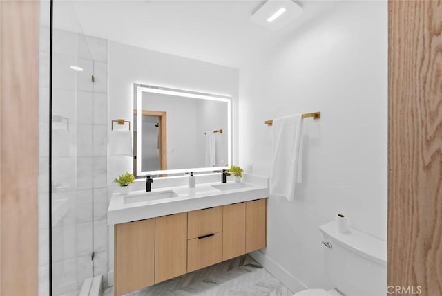 full bath featuring marble finish floor, a sink, toilet, and double vanity