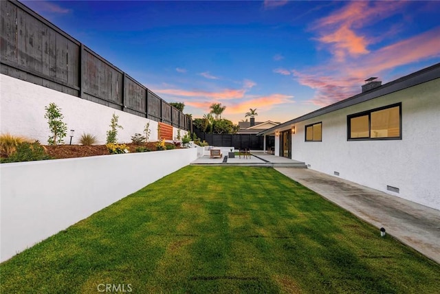 yard at dusk with a patio area and a fenced backyard