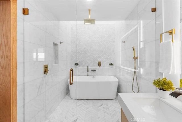 full bath with a freestanding tub, a marble finish shower, and tile walls