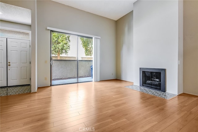 unfurnished living room with light wood-type flooring and a fireplace with flush hearth