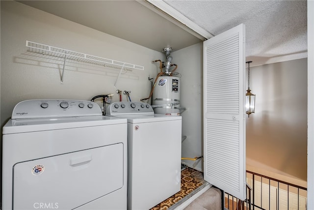 clothes washing area with water heater, separate washer and dryer, and a textured ceiling