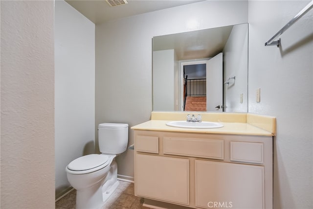 half bath with toilet, visible vents, baseboards, vanity, and tile patterned floors