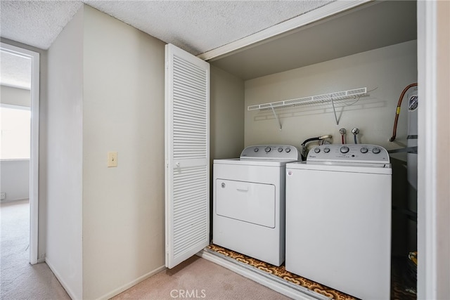 washroom with a textured ceiling, light carpet, laundry area, separate washer and dryer, and baseboards