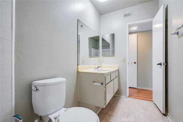 bathroom with baseboards, visible vents, vanity, and toilet