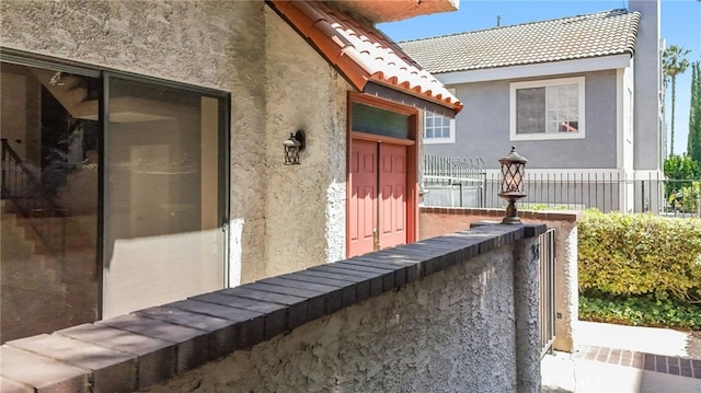 exterior space featuring a tile roof, fence, and stucco siding