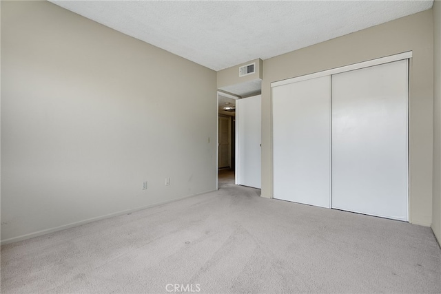 unfurnished bedroom with a textured ceiling, a closet, visible vents, and carpet flooring