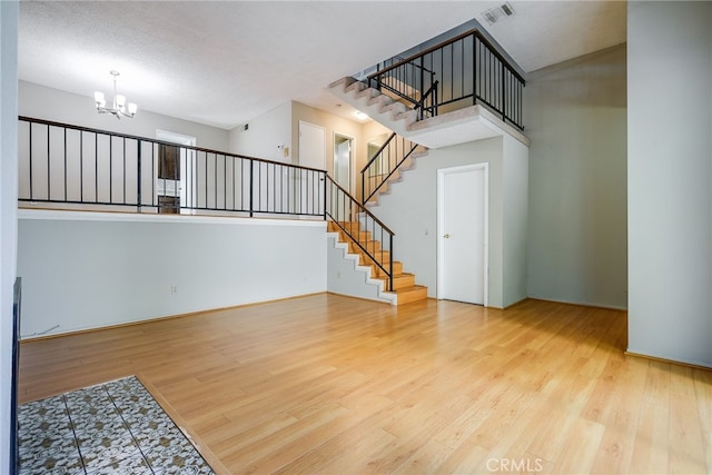 interior space with visible vents, a high ceiling, wood finished floors, a chandelier, and stairs