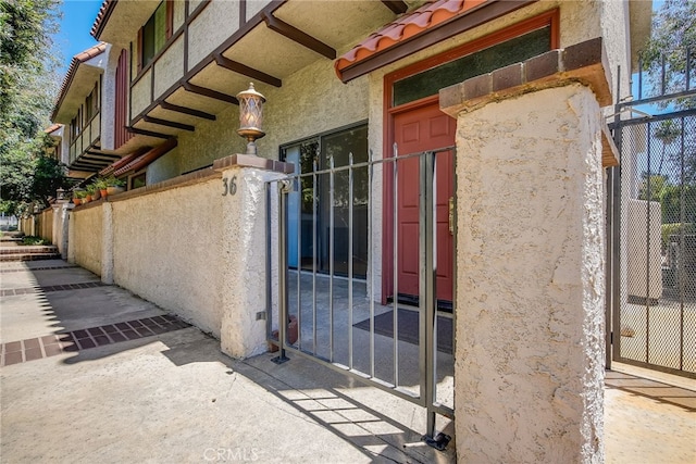 doorway to property featuring a tiled roof and stucco siding