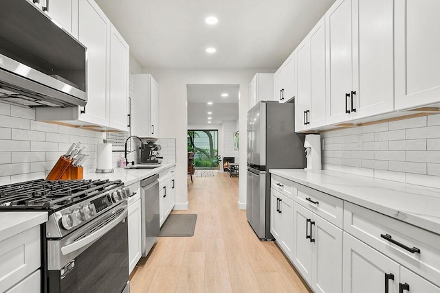 kitchen featuring recessed lighting, a sink, white cabinetry, light wood-style floors, and appliances with stainless steel finishes