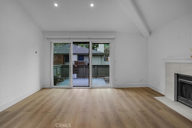 unfurnished living room featuring vaulted ceiling with beams, recessed lighting, a tiled fireplace, wood finished floors, and baseboards