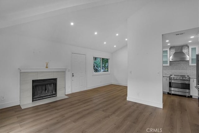 unfurnished living room featuring baseboards, wood finished floors, a fireplace, and vaulted ceiling