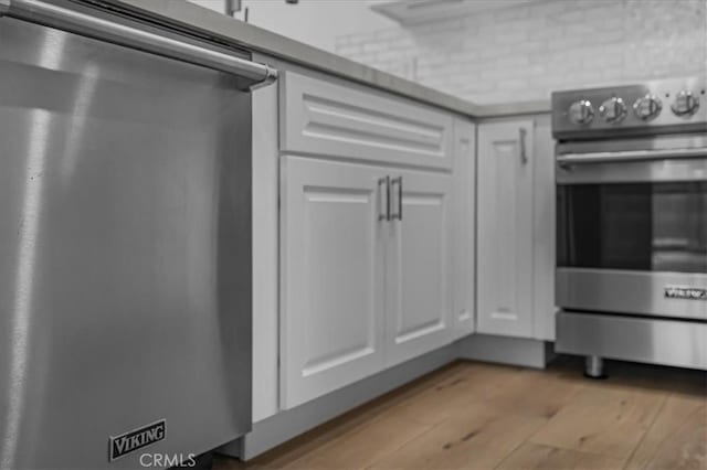 interior space with appliances with stainless steel finishes, white cabinets, wood finished floors, and light countertops