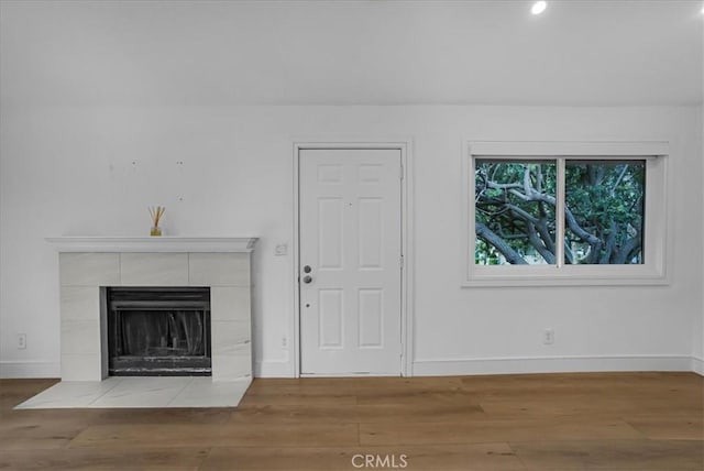unfurnished living room featuring a fireplace, baseboards, and wood finished floors