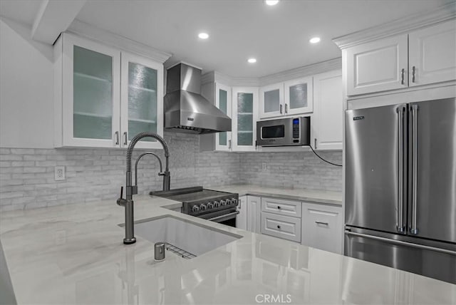 kitchen with white cabinetry, stainless steel appliances, wall chimney exhaust hood, and a sink