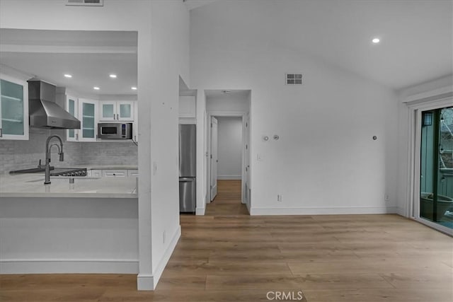 kitchen with light countertops, visible vents, appliances with stainless steel finishes, white cabinetry, and wall chimney exhaust hood