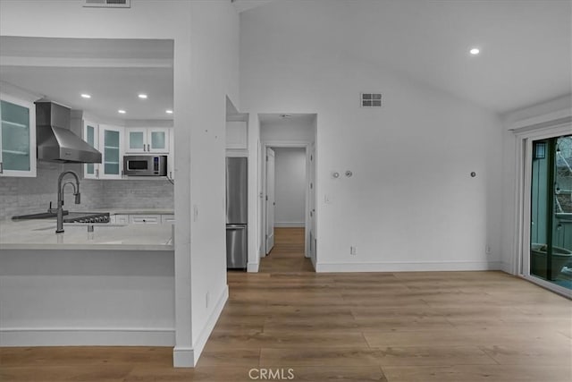 kitchen featuring visible vents, white cabinets, wall chimney range hood, light countertops, and appliances with stainless steel finishes