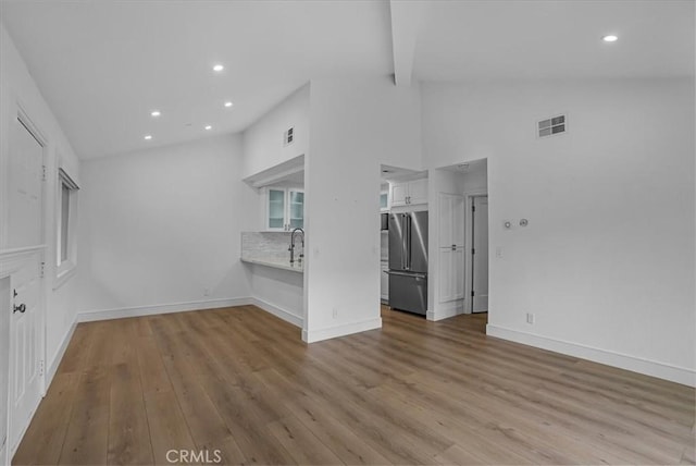 unfurnished living room with recessed lighting, visible vents, baseboards, and wood finished floors