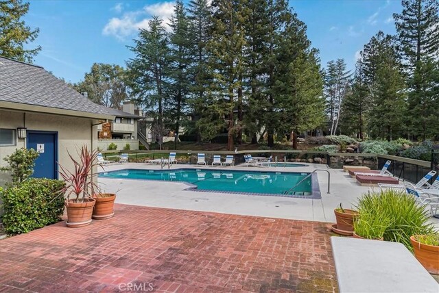 community pool with a patio and fence