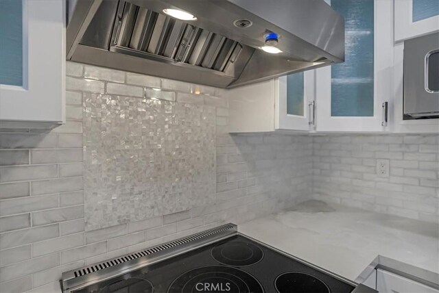 kitchen featuring glass insert cabinets, white cabinetry, range, and exhaust hood