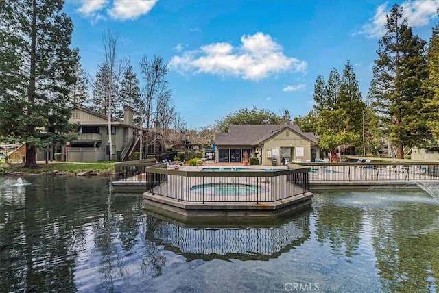 exterior space featuring a community pool, a patio area, and a water view
