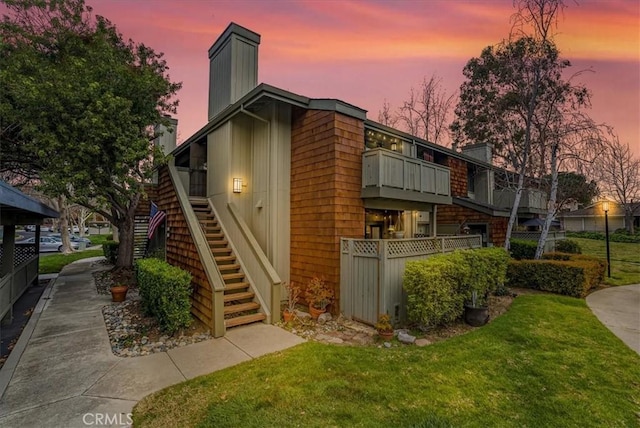 exterior space with a chimney, a yard, fence, and stairway