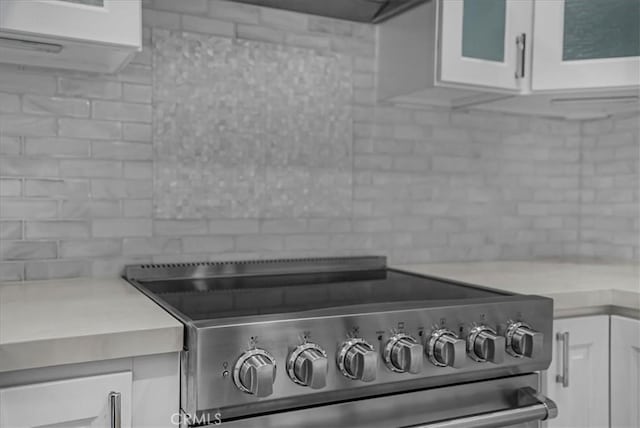 details featuring light countertops, backsplash, white cabinets, and electric stove