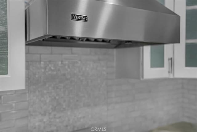 interior details featuring wall chimney range hood and white cabinets