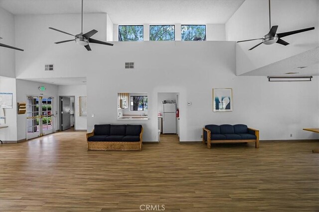 living area featuring visible vents, ceiling fan, baseboards, and wood finished floors