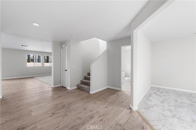 interior space with wood finished floors, visible vents, baseboards, and stairs