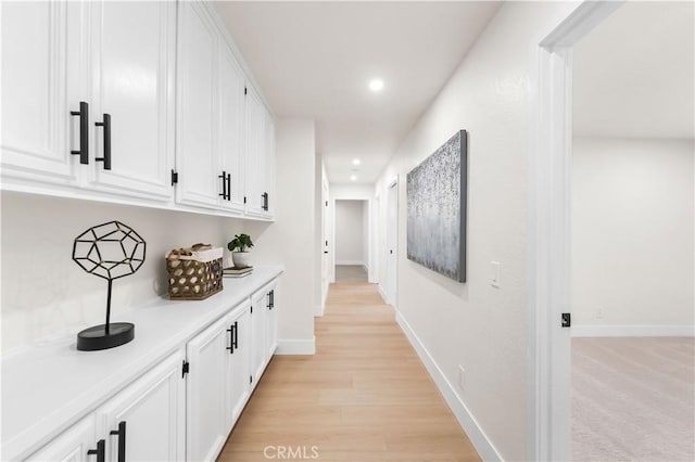 corridor featuring light wood-type flooring, baseboards, and recessed lighting