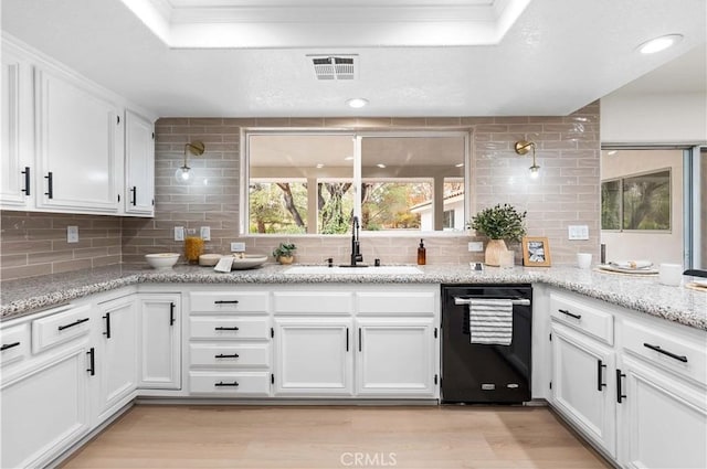 kitchen with dishwasher, visible vents, light wood finished floors, and a sink