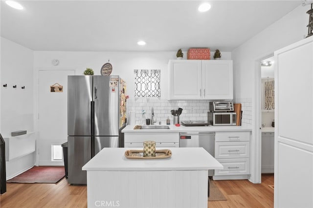 kitchen featuring light countertops, light wood-style flooring, white cabinets, stainless steel appliances, and a sink