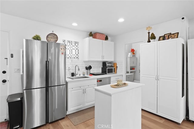 kitchen with light wood-style flooring, a sink, appliances with stainless steel finishes, white cabinets, and light countertops