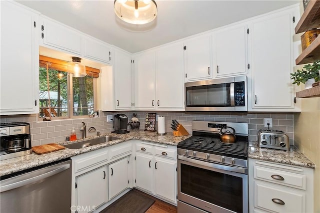 kitchen featuring appliances with stainless steel finishes, backsplash, a sink, and white cabinetry