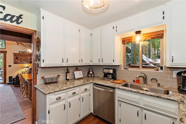 kitchen featuring stainless steel dishwasher, a sink, a wealth of natural light, and decorative backsplash