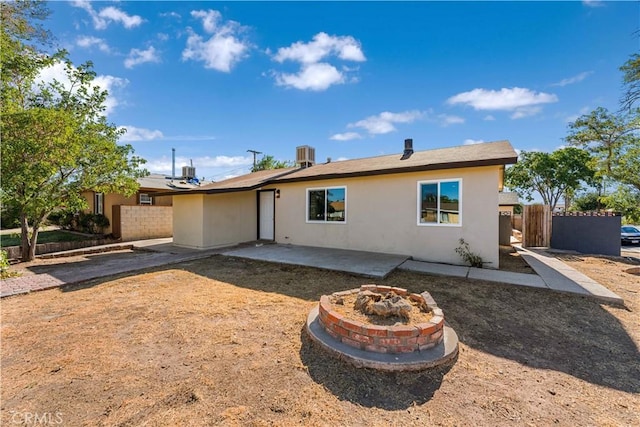 rear view of house featuring central AC unit, stucco siding, fence, and a patio