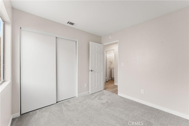 unfurnished bedroom with a closet, visible vents, baseboards, and carpet flooring