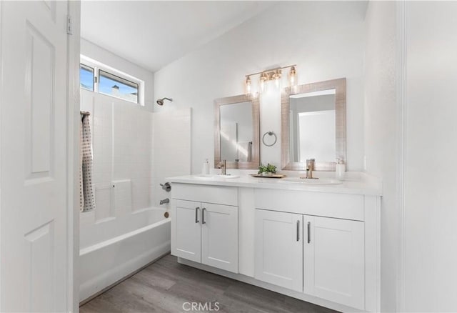 full bathroom with wood finished floors, tub / shower combination, a sink, and double vanity