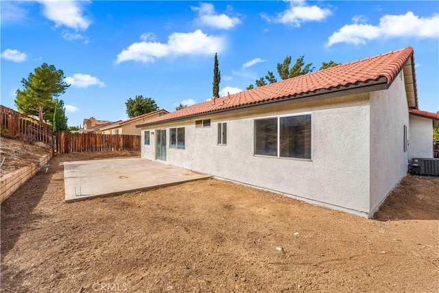 rear view of property with a tile roof, stucco siding, central AC unit, a patio area, and a fenced backyard