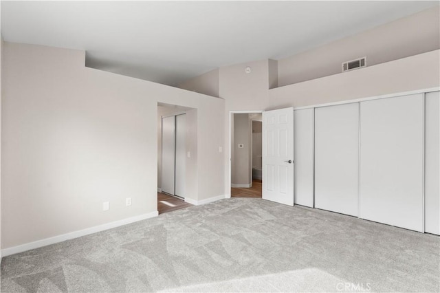 unfurnished bedroom featuring baseboards, visible vents, vaulted ceiling, and carpet flooring