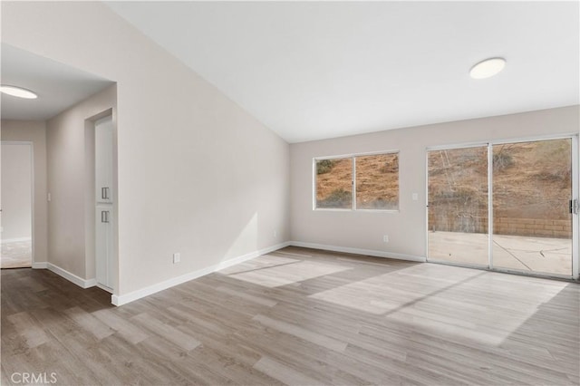 unfurnished room with lofted ceiling, baseboards, and wood finished floors