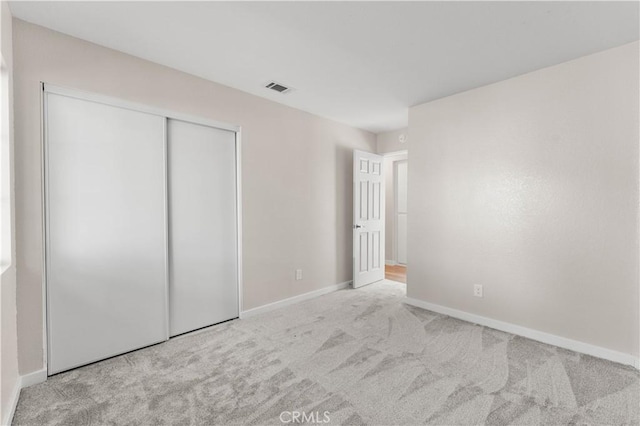 unfurnished bedroom featuring a closet, visible vents, baseboards, and carpet flooring