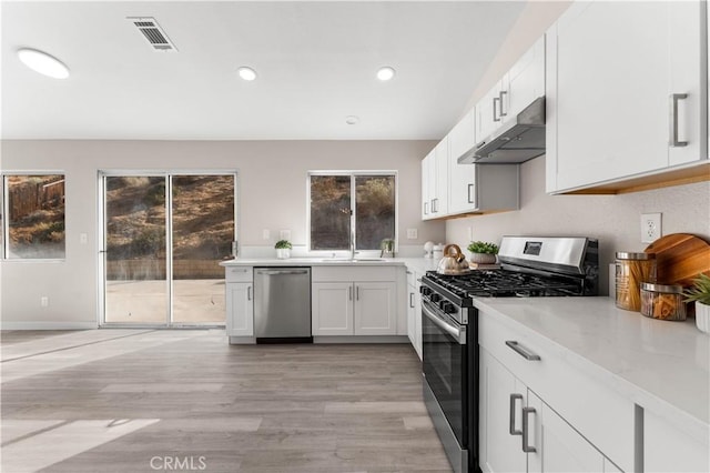 kitchen with light wood finished floors, visible vents, white cabinets, stainless steel appliances, and under cabinet range hood